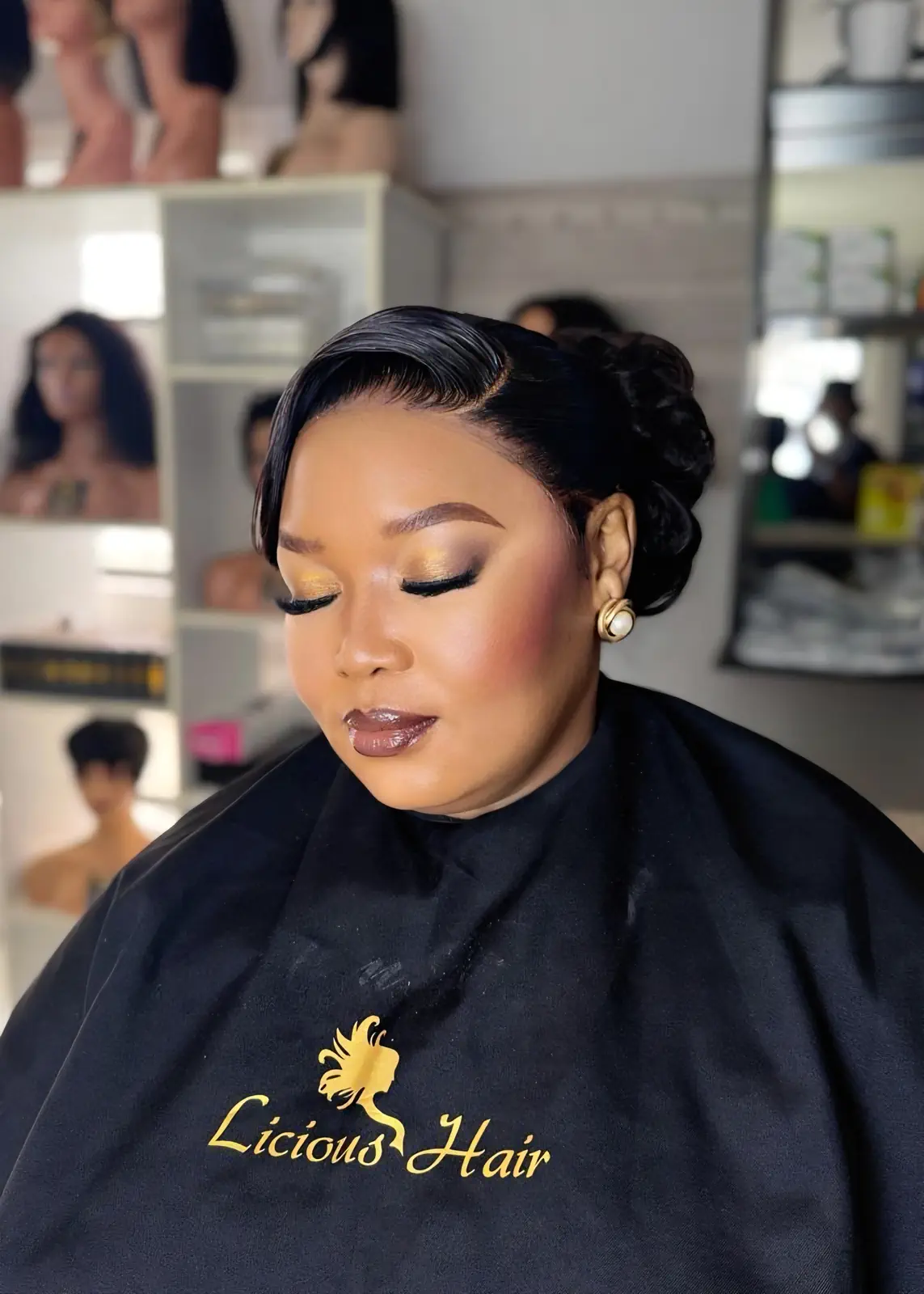 Woman with a polished side-parted updo and sculpted waves at Licious Hair salon