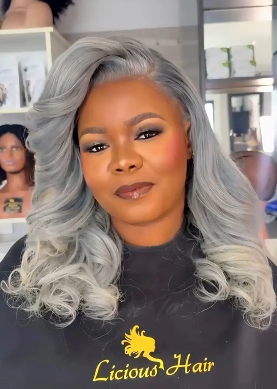 Woman wearing shoulder-length silver-grey hair styled in voluminous curls at Licious Hair salon