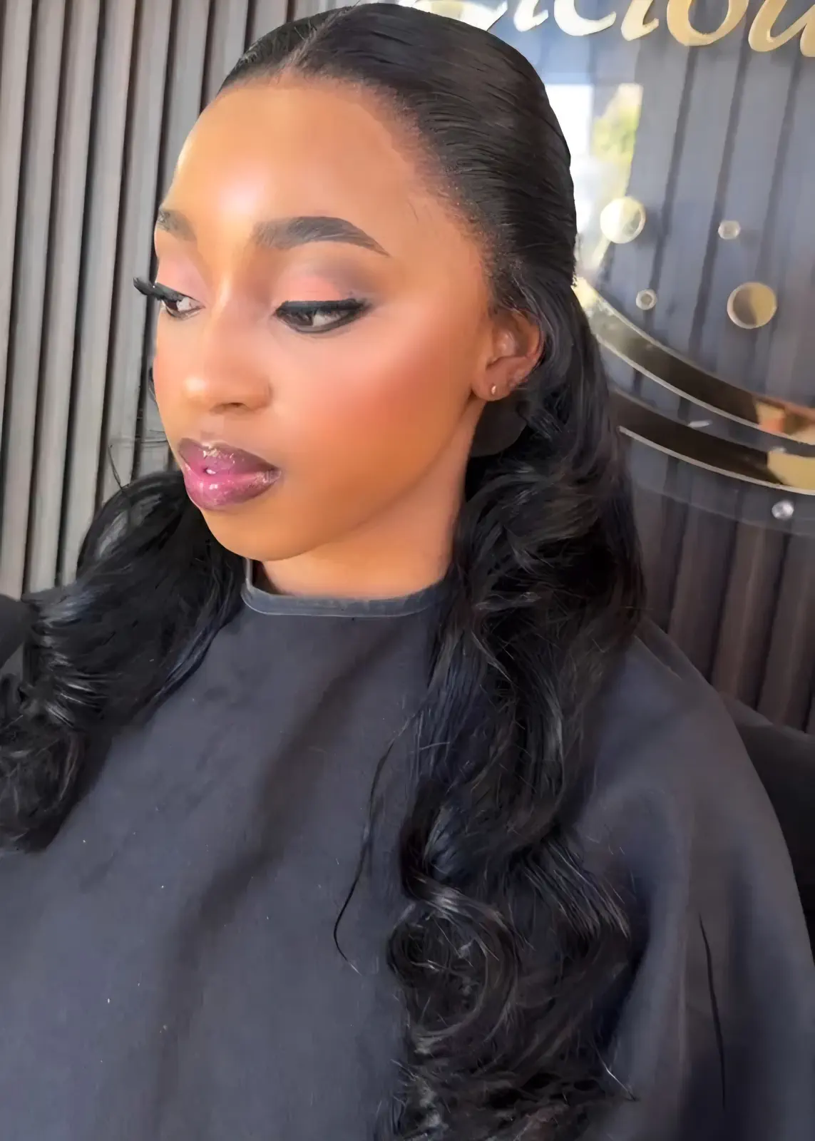 Woman wearing a sleek black ponytail with long cascading curls at Licious Hair salon