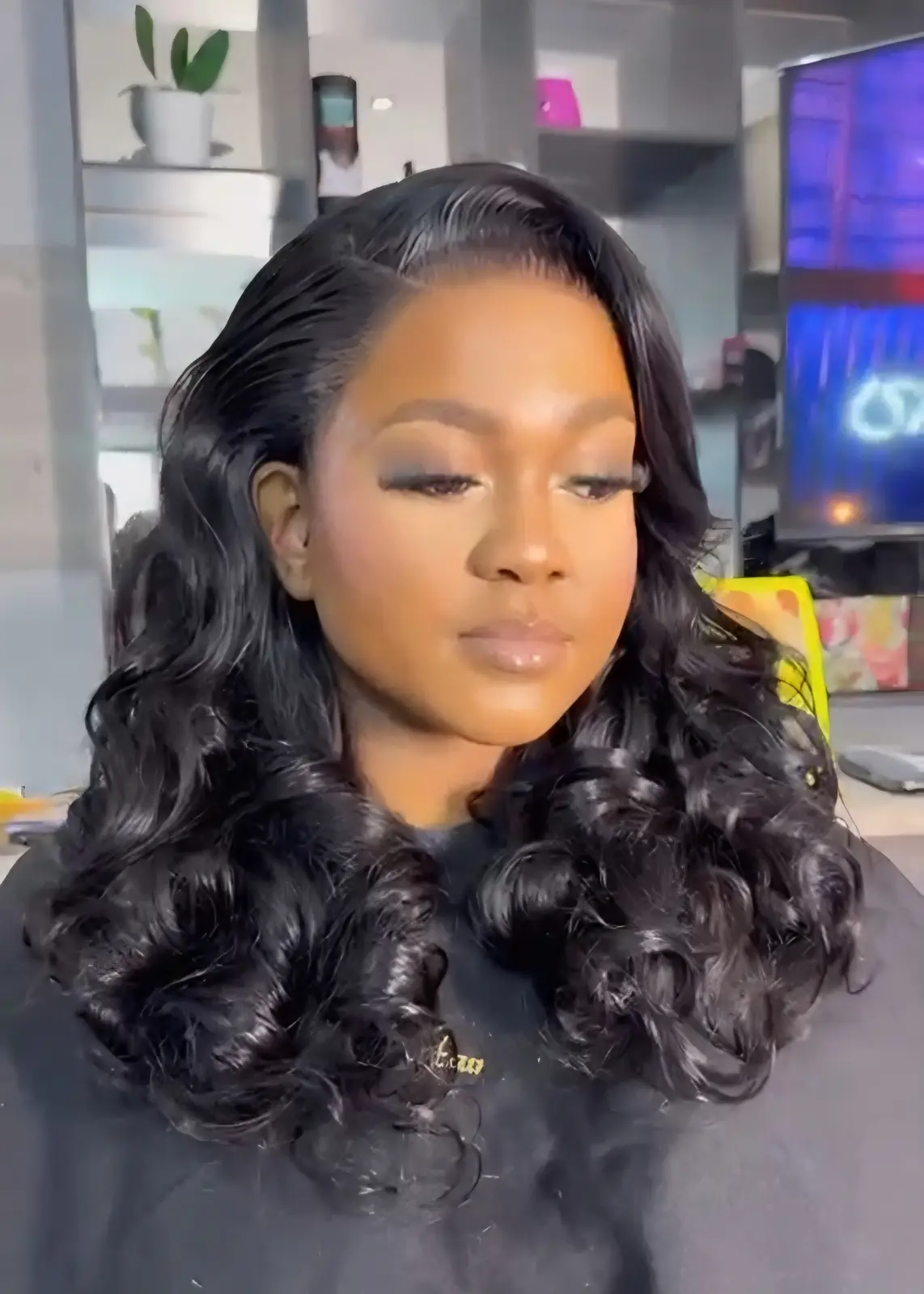 Woman wearing voluminous, side-parted black curls at Licious Hair salon